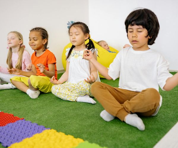 Group of kids laughing while trying a simple yoga balance exercise.
